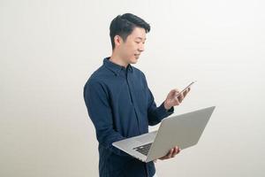 asiatisk man talar smartphone eller mobiltelefon och hand som håller bärbar dator foto