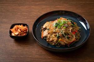 japchae eller wokade koreanska vermicelli nudlar med grönsaker och fläsk toppad med vit sesam foto