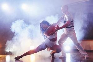 skickliga dansare som uppträder i det mörka rummet under konsertens ljus och rök. sensuellt par som utför en konstnärlig och känslomässig samtida dans foto