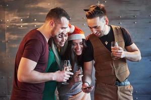 glada gamla vänner kommunicera med varandra och telefonklocka, med glas champagne i nyårsfest. begreppet underhållning och livsstil. wifi-anslutna människor foto