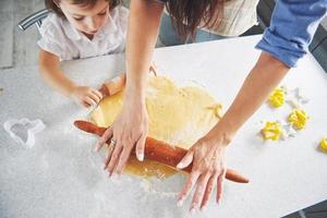 lycklig familj förberedelse semester mat koncept. familjen lagar julkakor. händerna på mor och dotter som förbereder degen på bordet. lycklig familj i att göra kakor hemma foto