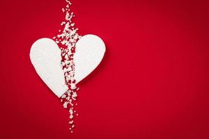 bakgrund med vitt brutet styrofoam hjärta på en röd bakgrund foto