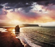 den svarta sandstranden och bergen reynisfjara från udden vid solnedgången på Island foto