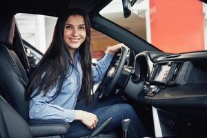 bilaffärer, bilförsäljning, konsumentism och folkkoncept - glad kvinna tar bilnyckel från återförsäljare i bilmässa eller salong foto