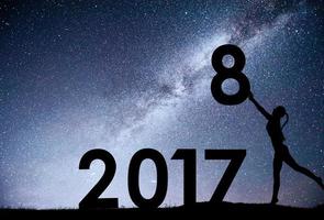 siluett ung flicka. gott nytt år 2018. bakgrund av Vintergatan galaxen på en ljus stjärna mörk himmel ton. konceptändringsår 2017 till 2018 foto