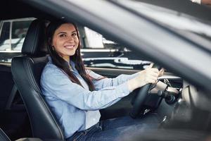 bilaffärer, bilförsäljning, konsumentism och folkkoncept - glad kvinna tar bilnyckel från återförsäljare i bilmässa eller salong foto