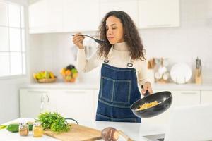 latinsk kvinna som filmar och lagar mat i köket foto