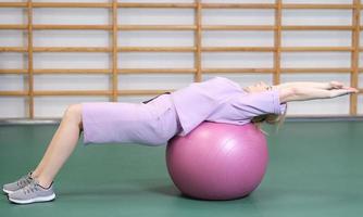kvinna träning med fitball, kinky kropp, flexibilitet och stretching, fitness på gym, riktiga människor foto