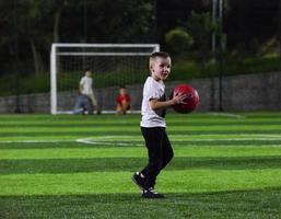 liten pojke spelar boll foto