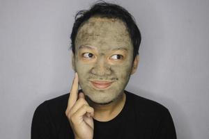 asiatisk man tänkte och dag drömde när han använder skönhet ansiktsmask foto
