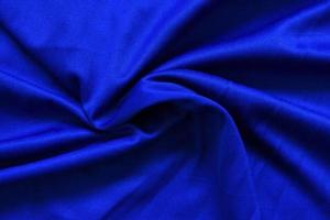 abstrakt mörkblått skrynkligt tyg texturbakgrund - slät elegant blått siden, våg av lyxigt tyg i satäng foto