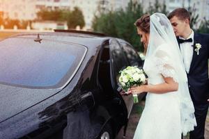 lyckliga brudparet nära bilen. foto
