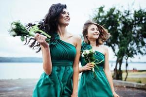 glada unga kvinnor på ett bröllop med buketter av blommor foto
