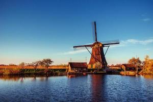 färgglad vårdag med traditionella holländska väderkvarnar kanal i ro foto