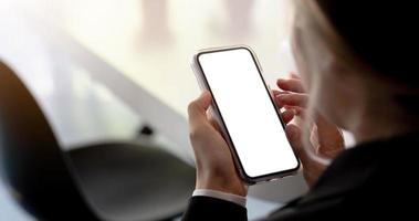 närbild av en kvinna hand som håller en smartphone vit skärm är tom bakgrunden är blurred.mockup. foto
