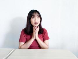 ung asiatisk kvinna tänkande gest tittar ovanför isolerad på vit bakgrund foto