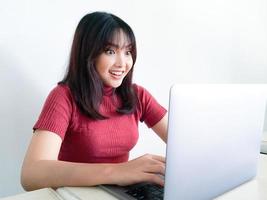 asiatisk kvinna bär röd skjorta med laptop känsla upphetsade skrik av glädje och lycka, överraskning, vinnaruttryck, vit bakgrund. indonesiska kvinnor foto