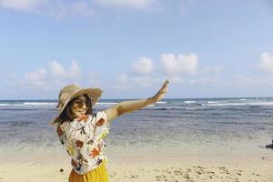 porträtt av glad leende asiatisk kvinna på stranden bär hatt foto