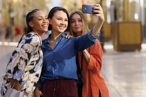 innehåll unga multiracial kvinnliga turister ler på att ta selfie på smartphone foto