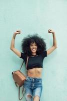 rolig svart kvinna med afro hår höja armarna utomhus foto