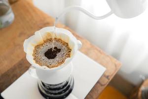 droppa kaffe, hälla ett varmt vatten över ett dropp kaffe på bordet foto