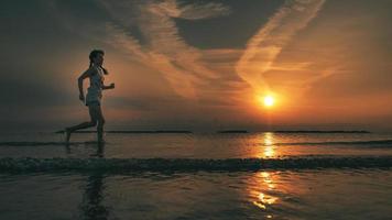 en ung kvinna springer till stranden i gryningen foto