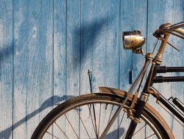gammal cykel parkerad framför blå plankgolvbakgrund foto