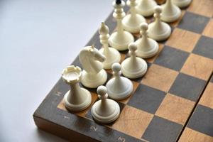 ett gammalt schackbräde med vita och svarta pjäser foto