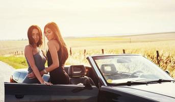 två sexig brunett kvinna som står nära hennes bil foto