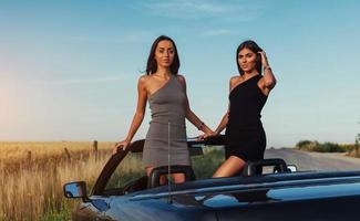 vackra två kvinnor som sitter i en cabriolet foto