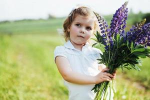 flicka med vackra blå blommor på en solig sommarkväll. foto