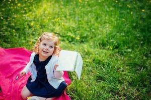 glad liten flicka i en sommarpicknick i parken. foto