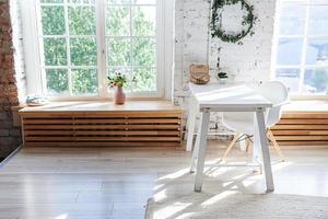 elegant loft modern hemmakontorsinredning. rymlig designlägenhet med ljusa väggar stora fönster och skrivbord. ren modern inredning med eleganta möbler i minimalistisk skandinavisk stil. foto