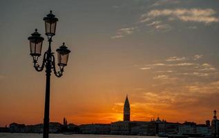 Venedig i solnedgången med reflektioner i havet foto