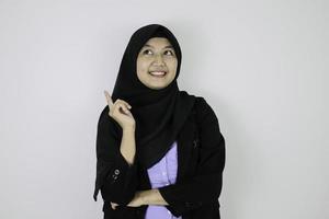 glad och dagdrömmande gest ung asiatisk islam kvinna som bär huvudduk. foto