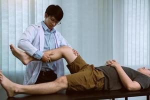 fysioterapeuter använder händerna för att greppa patientens lår för att kontrollera smärta och massage på kliniken. foto