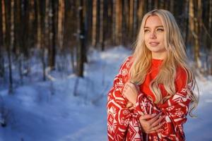 vacker glad blond kvinna i röd tröja i vinterskogen foto