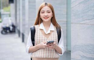 ung asiatisk kvinna som använder smartphone på gatan foto