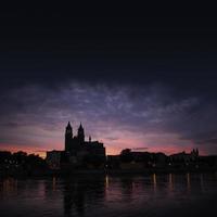 siluett av ett medeltida slott vid vacker blodig solnedgång i magdeburgs historiska centrum, gamla stan, floden Elbe och den magnifika katedralen, Tyskland. foto