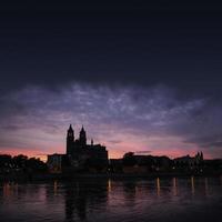 siluett av ett medeltida slott vid vacker blodig solnedgång i magdeburgs historiska centrum, gamla stan, floden Elbe och den magnifika katedralen, Tyskland. foto