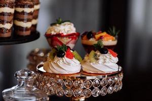 grädde desserter med bär på candy bar. bord med godis och godsaker för bröllopet eller födelsedagsfesten mottagning, dekoration dessertbord. läckra godis på godisbuffé. selektiv fokusering. foto