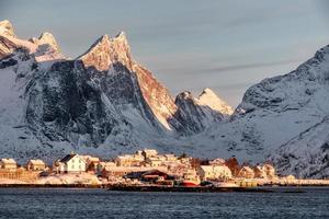 soluppgång på skandinavisk by med snö berg bakgrund på kusten foto