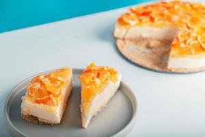 närbild detaljvy skivad orange cheesecake eller pudding, dekorerad med mogen orange frukt. foto