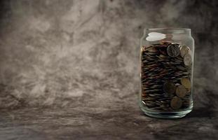 glasflaska med en flaska full av mynt att spara för framtida affärer. besparingsidé. foto
