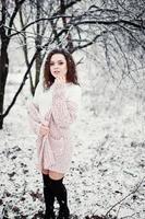 lockig brunett flicka bakgrund fallande snö, slitage på varm stickad tröja, svart minikjol och ullstrumpor. modell på vintern. modeporträtt vid snöväder. instagram-tonat foto. foto