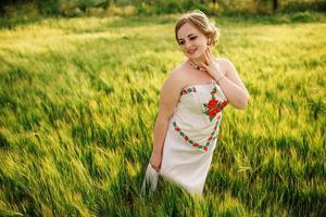 ung flicka på ukrainska nationella klänning poserade på krans fält. foto