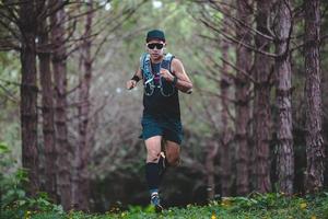 en man löpare av trail och idrottares fötter bär sportskor för trail löpning i skogen foto