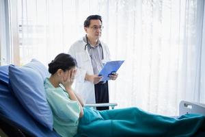 läkarna frågar och förklarar om sjukdomen för en kvinnlig patient som ligger i sängen på ett sjukhus. foto