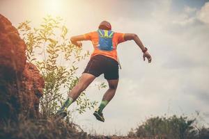 en man löpare av trail och atlets fötter bär sportskor för trail löpning i berget foto