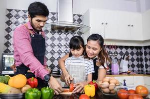 asiatiska familjer lagar mat och föräldrar lär sina döttrar att laga mat i köket hemma. familjeaktiviteter på semester och glad i rekreation koncept foto
